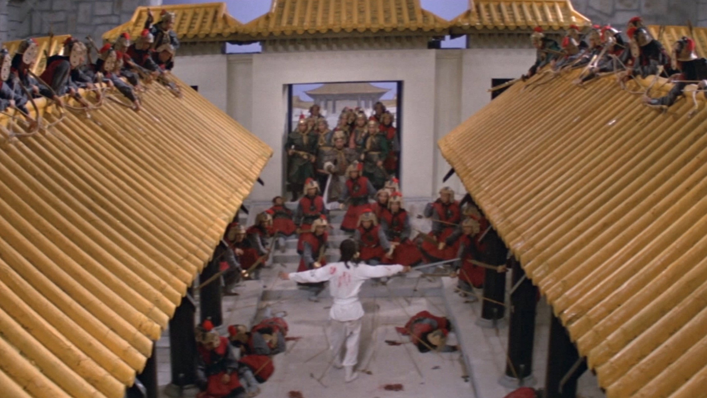 Shot from above we see a man in all white, facing away from us. He's covered in blood and wielding a sword. Surrounding him are dozens of soldiers wielding swords and bows.