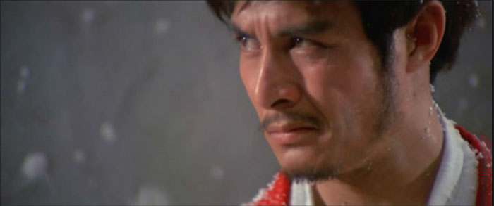 A close up of a man's face. He looks ready to fight. We can see that it is snowing lightly.
